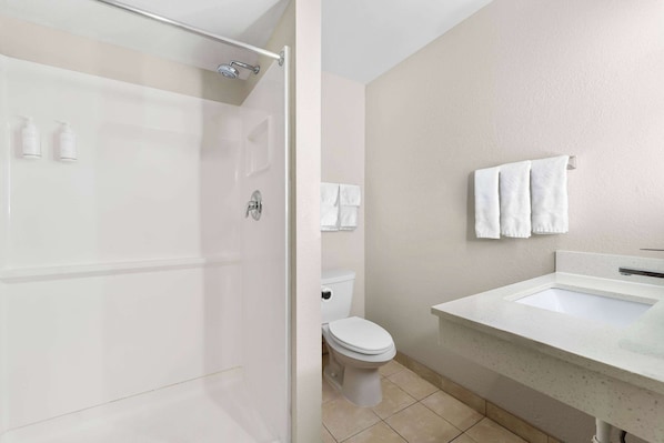 Une salle de bain moderne avec une douche à parois de verre, des toilettes blanches et un lavabo avec un miroir.