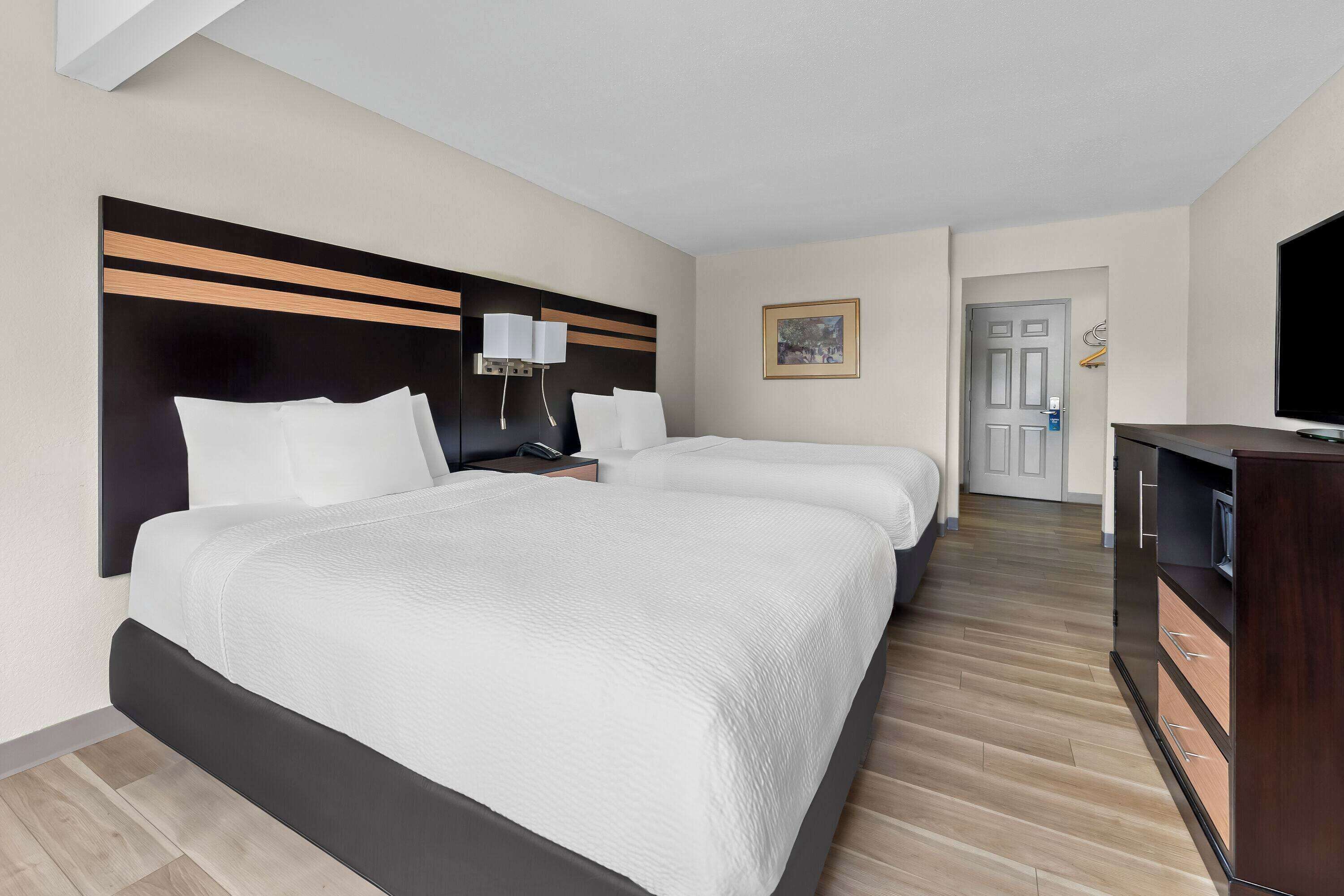 A hotel room with two beds, a TV, a desk, and a wardrobe.