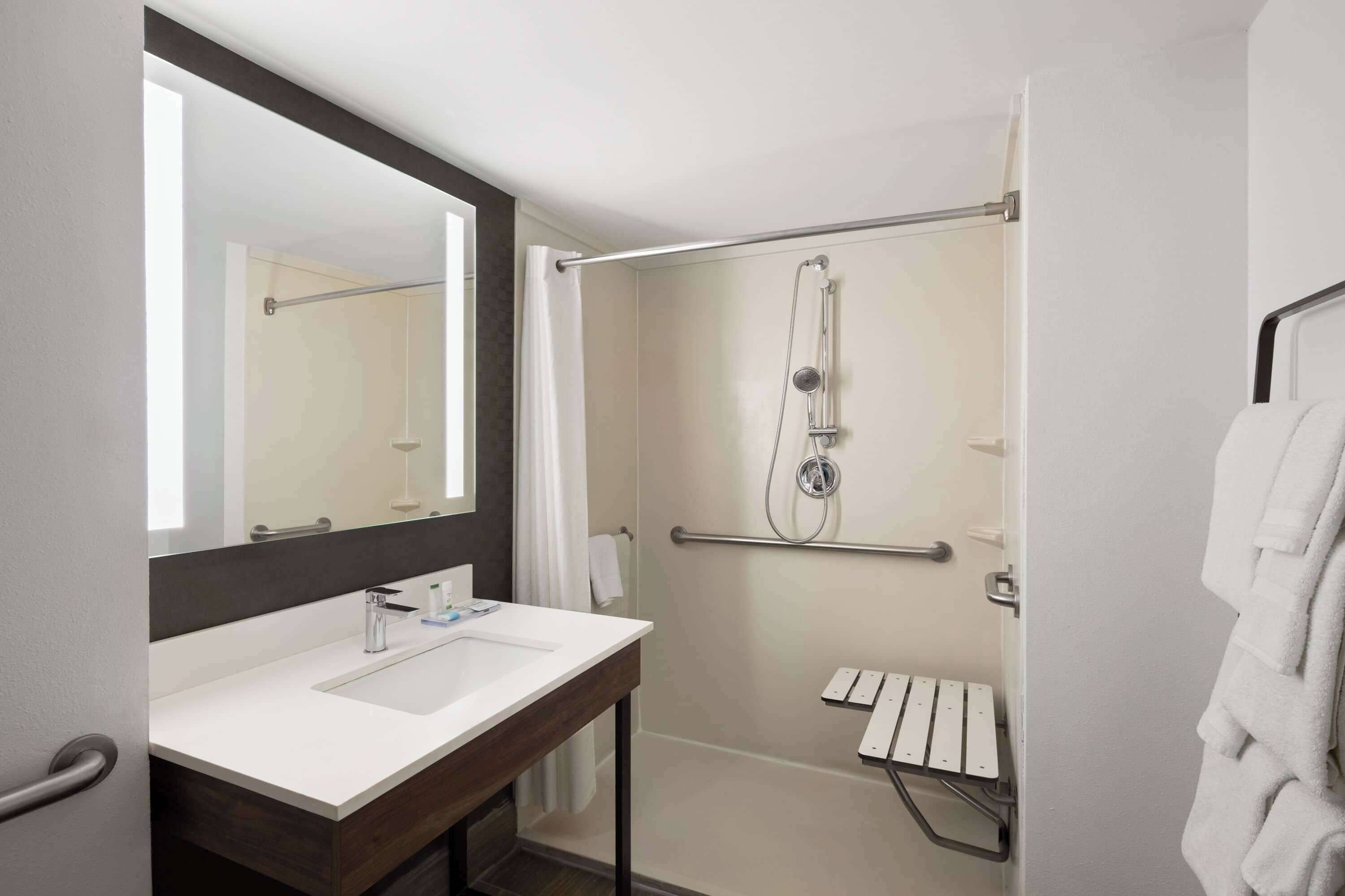 A modern bathroom with a white sink, a large mirror, and a glass-enclosed shower area.
