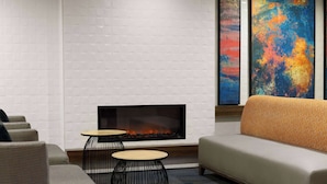 A modern lounge area with a fireplace, seating, and abstract art on the walls. - La Quinta Inn & Suites by Wyndham Kennewick (Kennewick)
