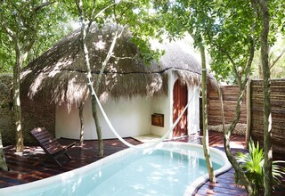 A pool area with a thatched-roof structure, wooden deck, and lounge chairs.