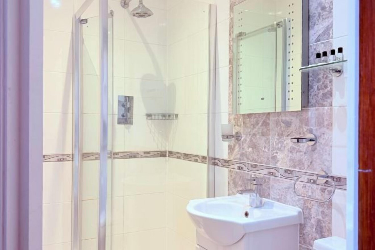 Ein Badezimmer mit Duschkabine, Waschbecken und Spiegel.