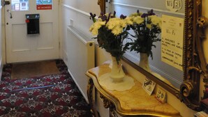 A hotel lobby with a "No Vacancies" sign, a "No Smoking" sign, a "Wi-Fi" sign, and a mirror with an ornate frame.
