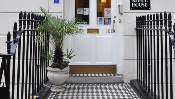 The exterior of Albro House Hotel with a checkered tile entrance, a potted plant, and a sign indicating the address 155.