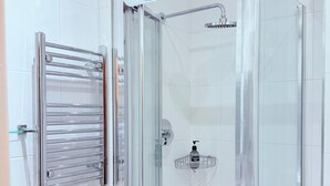 A modern bathroom with a glass-enclosed shower, a glass towel rack, and a white sink.
