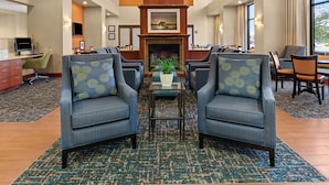 A hotel lobby with a fireplace, seating area, and a reception desk.