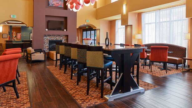 Eine Hotelhalle mit Bar, Sitzgelegenheiten, Kamin und großen Fenstern.