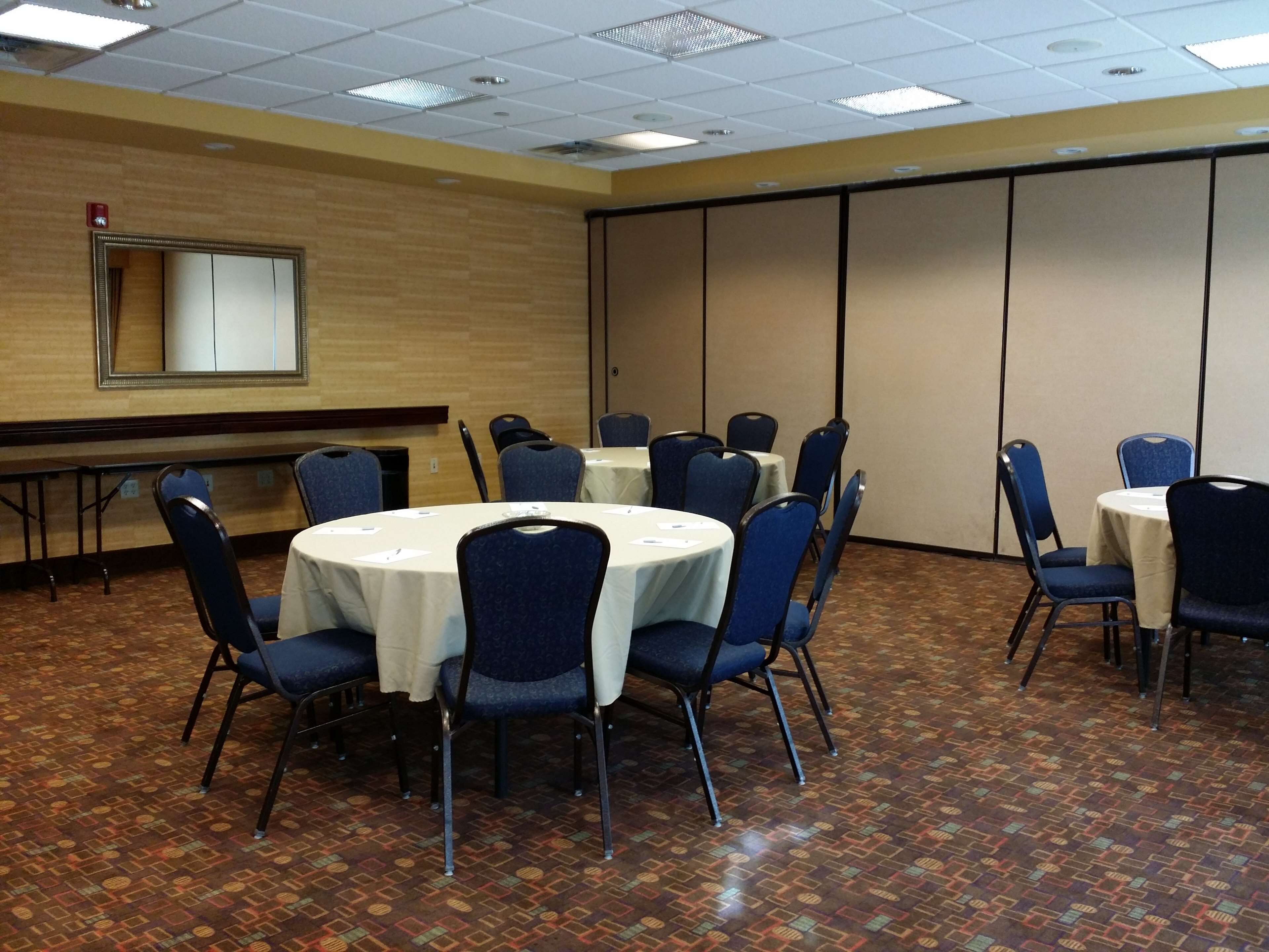 A conference room with round tables, blue chairs, and a wooden floor.