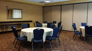 A conference room with round tables, blue chairs, and a wooden floor.