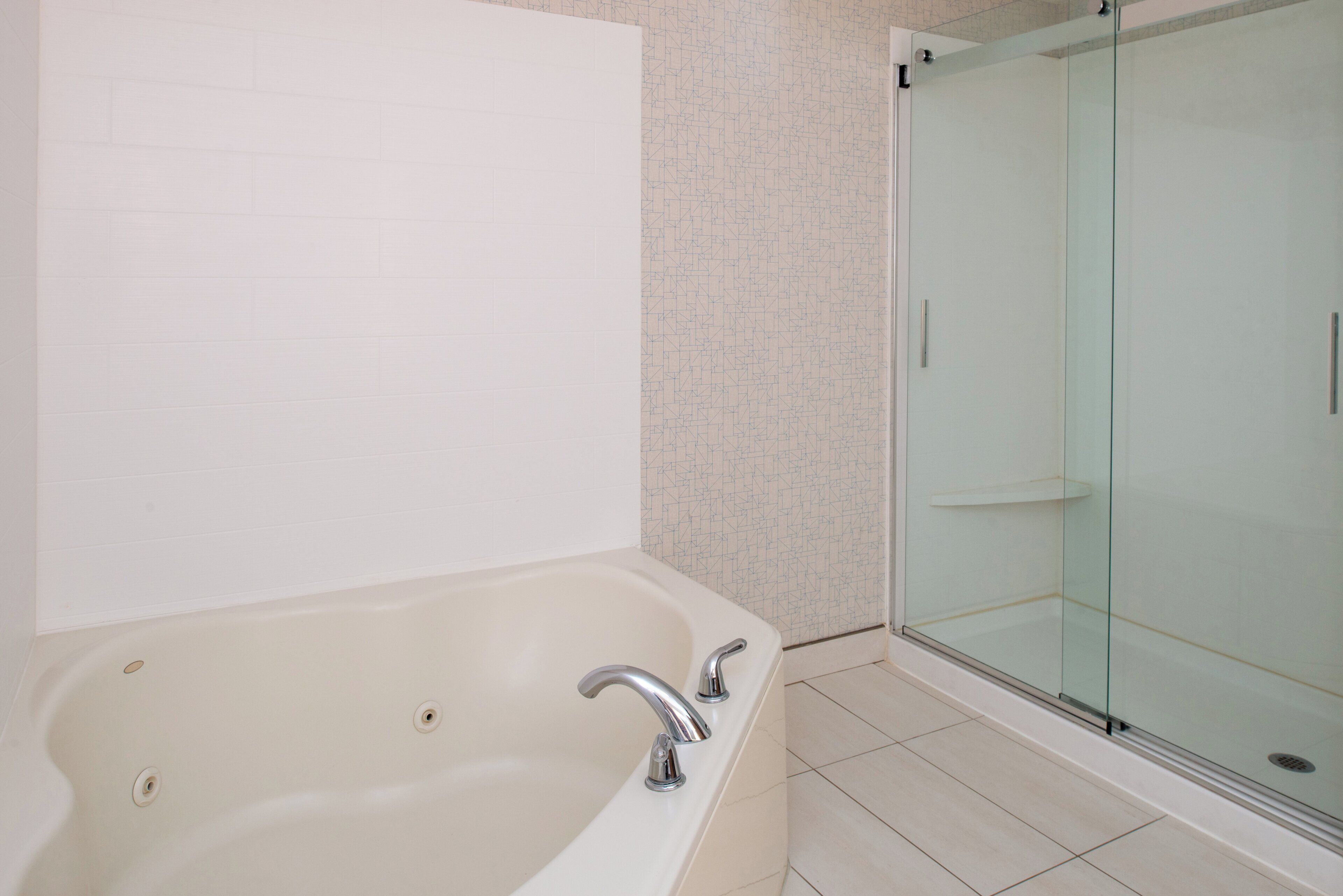 A bathroom with a bathtub, a glass shower enclosure, and tiled walls.