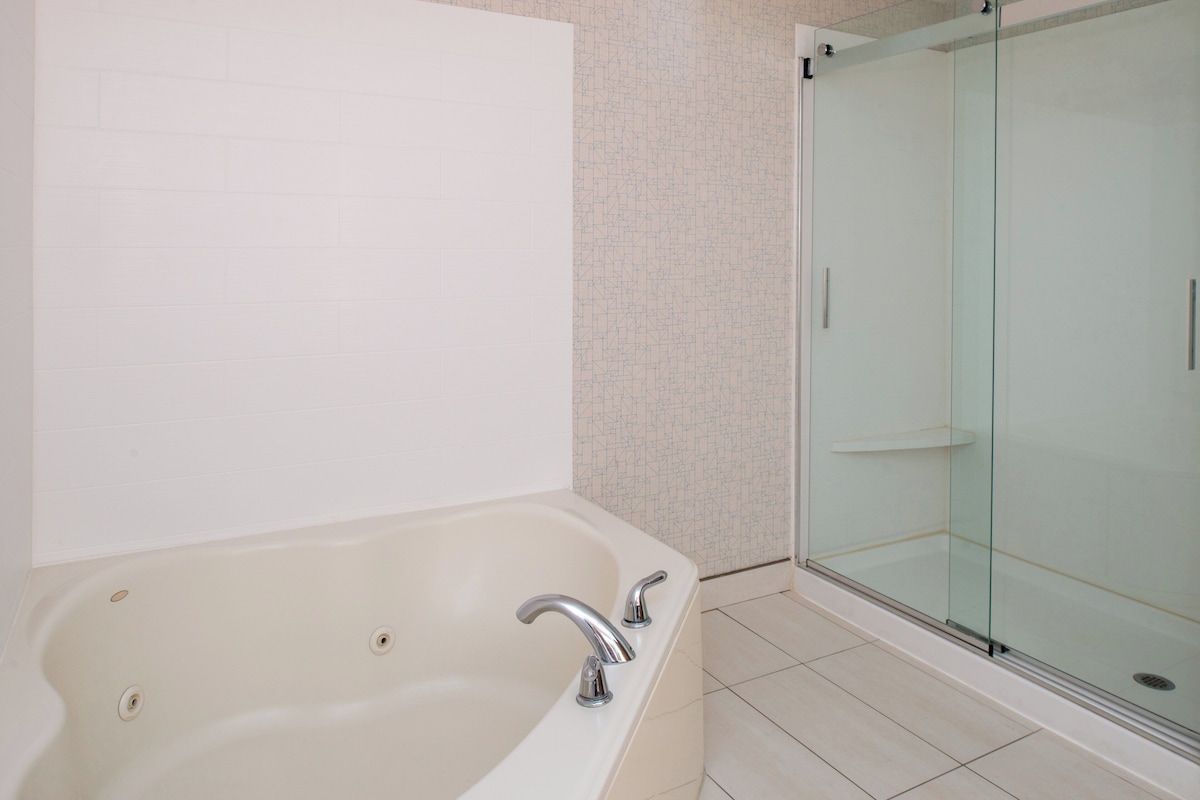 A bathroom with a bathtub, a glass shower enclosure, and tiled walls.