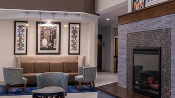 A modern lounge area with a fireplace, seating, and artwork on the walls.