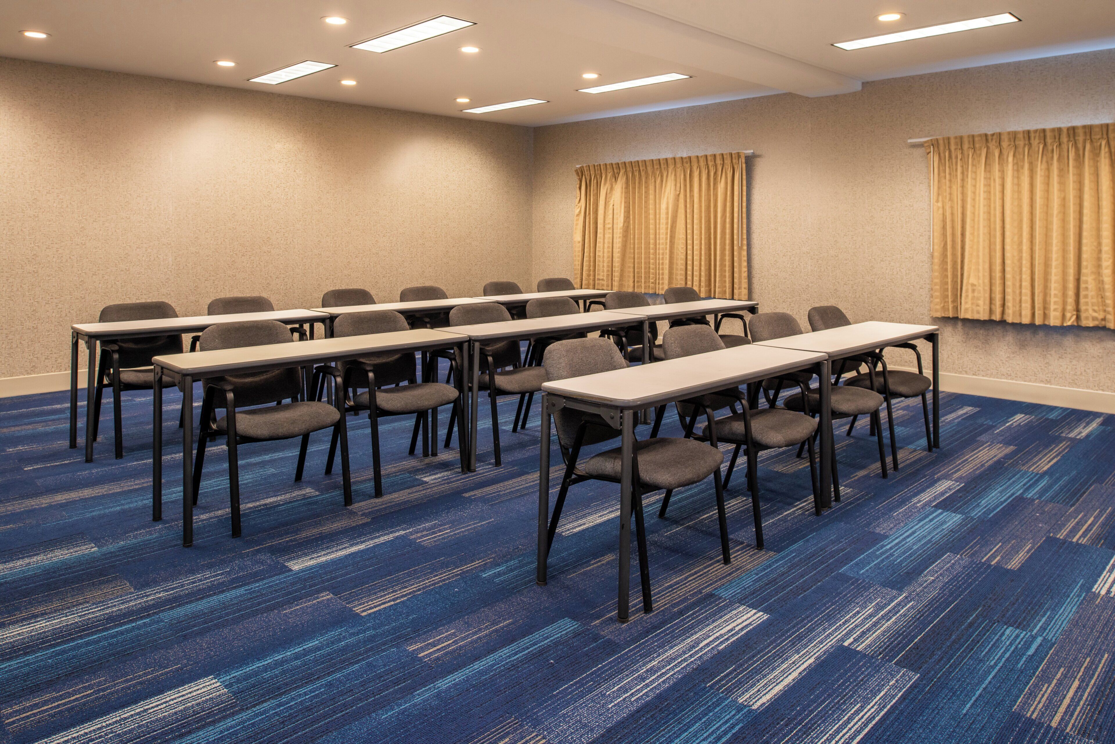 A conference room with a long table and chairs, carpeted floor, and ceiling lights.