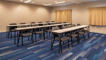 A conference room with a long table and chairs, carpeted floor, and ceiling lights.
