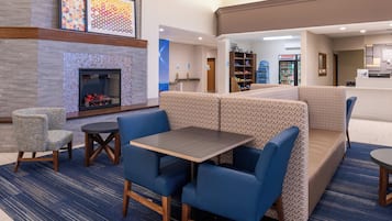 A hotel lobby with a fireplace, seating area, and a reception desk.