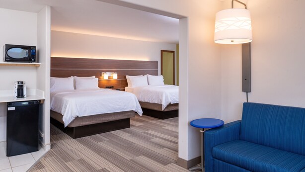 A hotel room with two beds, a microwave, a coffee maker, a blue sofa, and a small table. - Holiday Inn Express & Suites Gunnison by IHG (Gunnison)