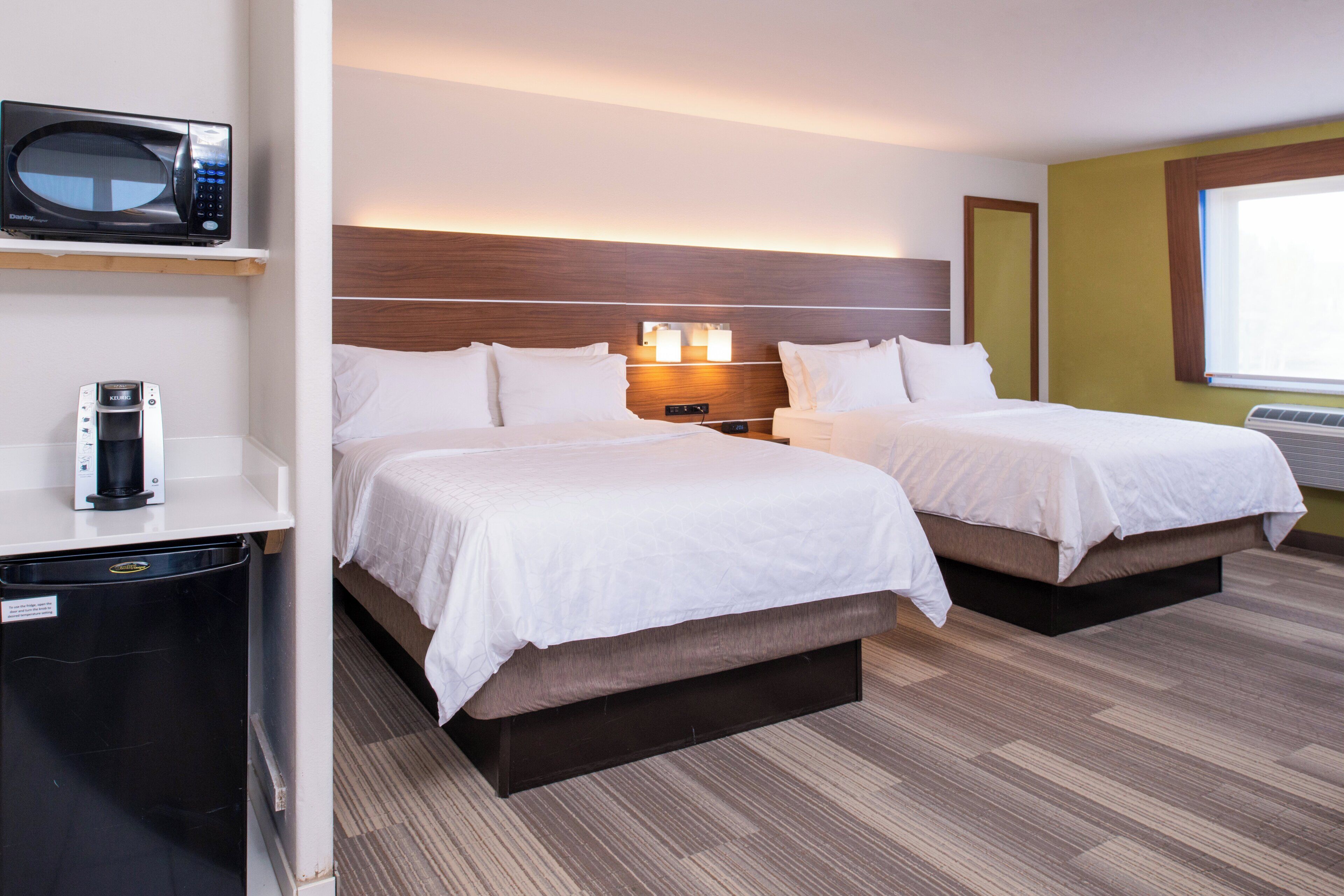 Habitación de hotel con dos camas, un minibar, un microondas y una lámpara de noche.