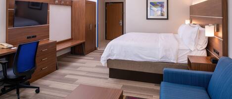 A hotel room with a bed, a desk with a chair, a TV, and a sofa.