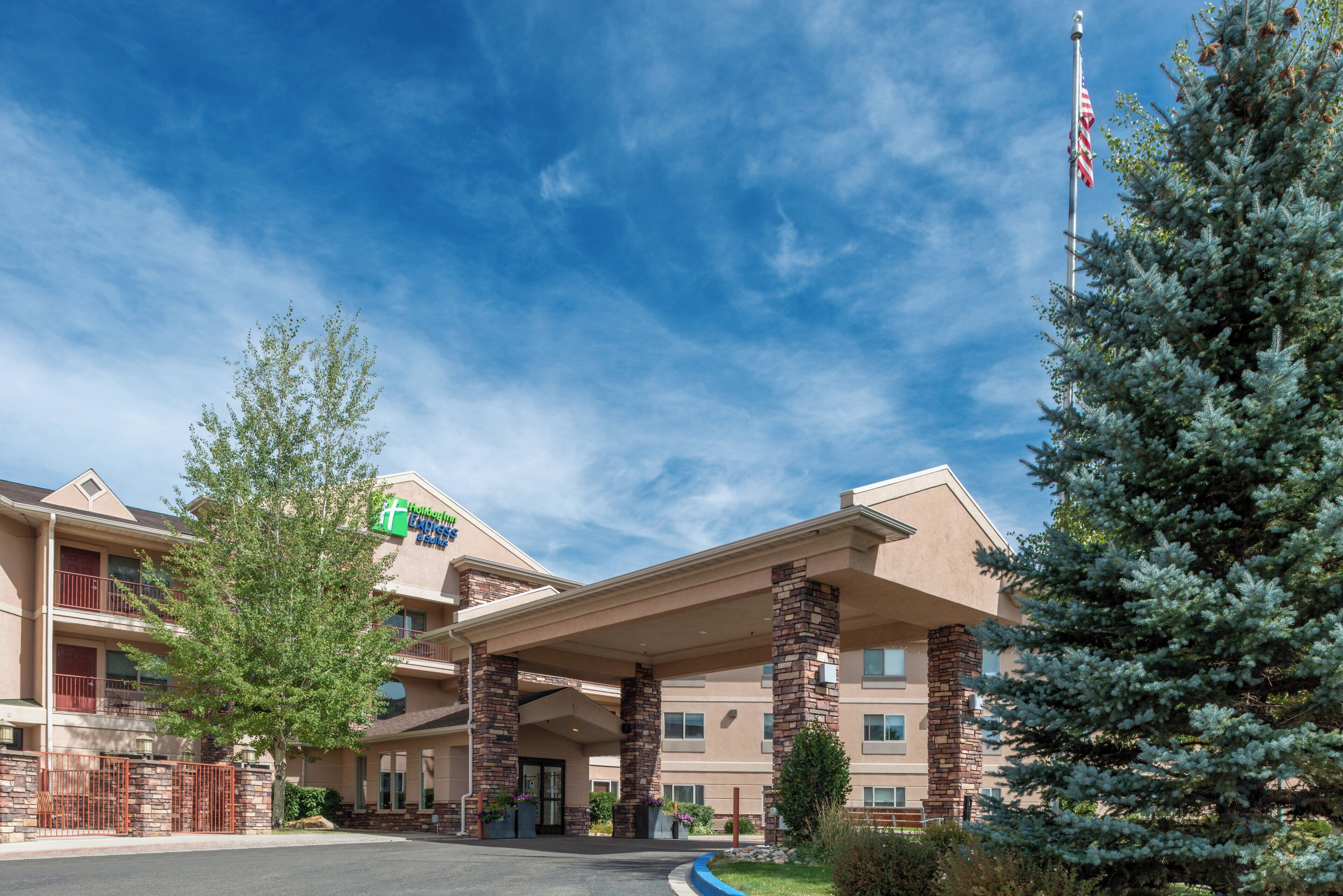 A hotel with a covered entrance, stone pillars, and a sign for Holiday Inn Express Suites.
