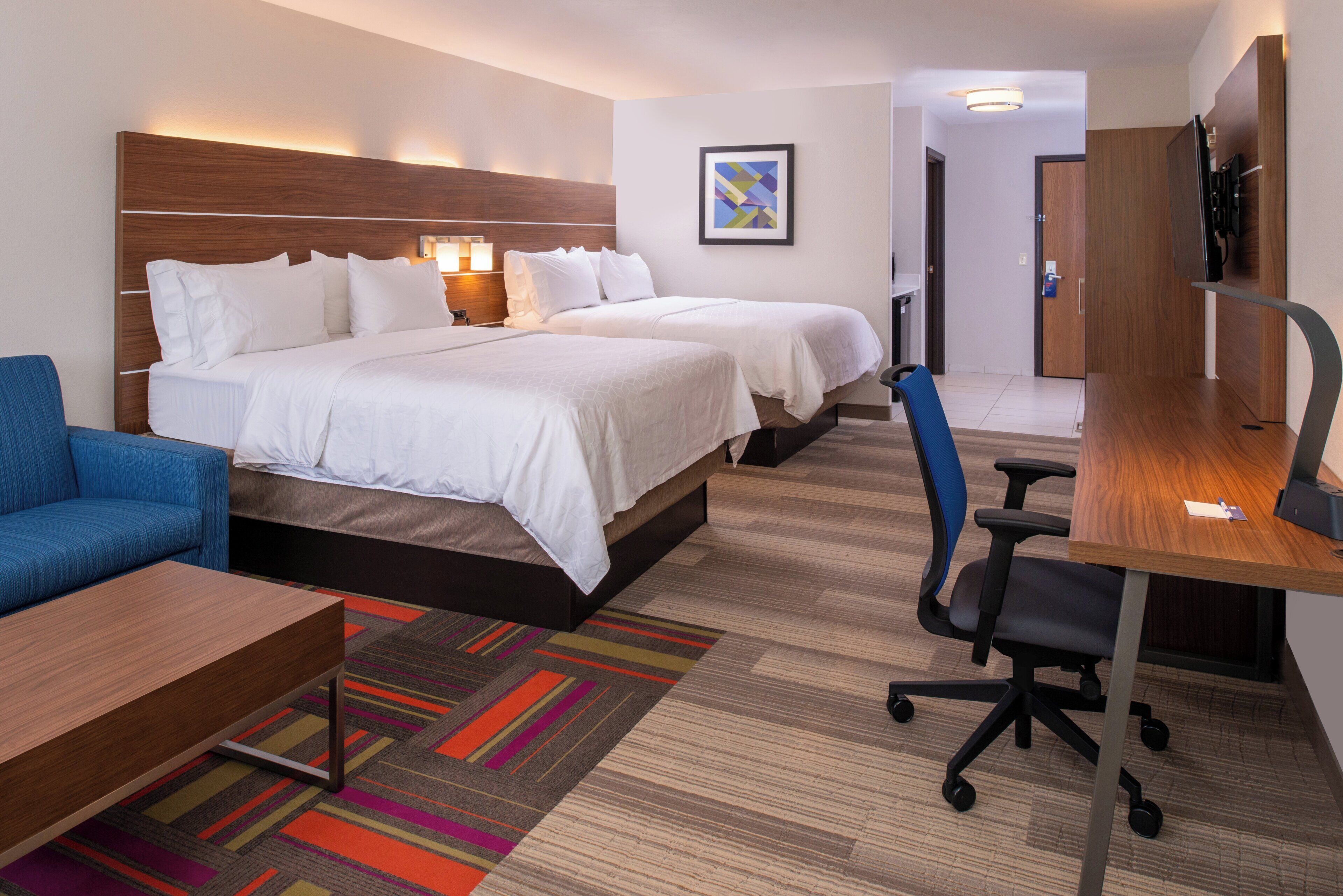A hotel room with a bed, a desk, a chair, and a small sofa.