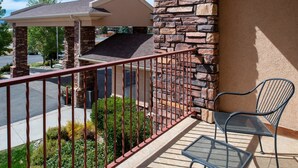 A balcony with a metal railing, a stone wall, and a metal chair. - Holiday Inn Express & Suites Gunnison by IHG (Gunnison)