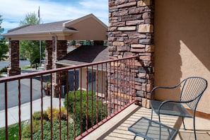 A balcony with a metal railing, a stone wall, and a metal chair.
