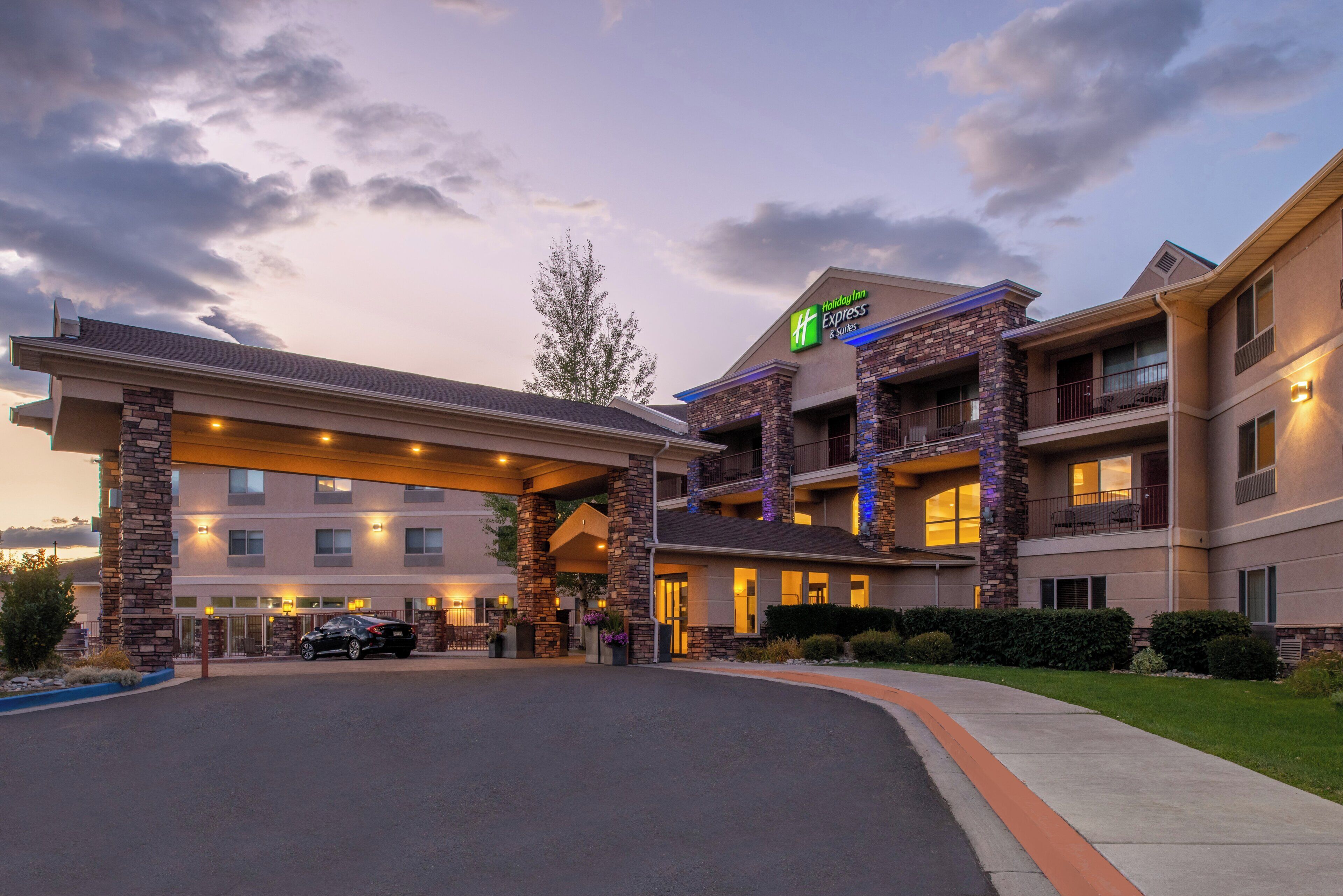 A Holiday Inn Express & Suites building with a stone facade, multiple balconies, and a covered entrance area.