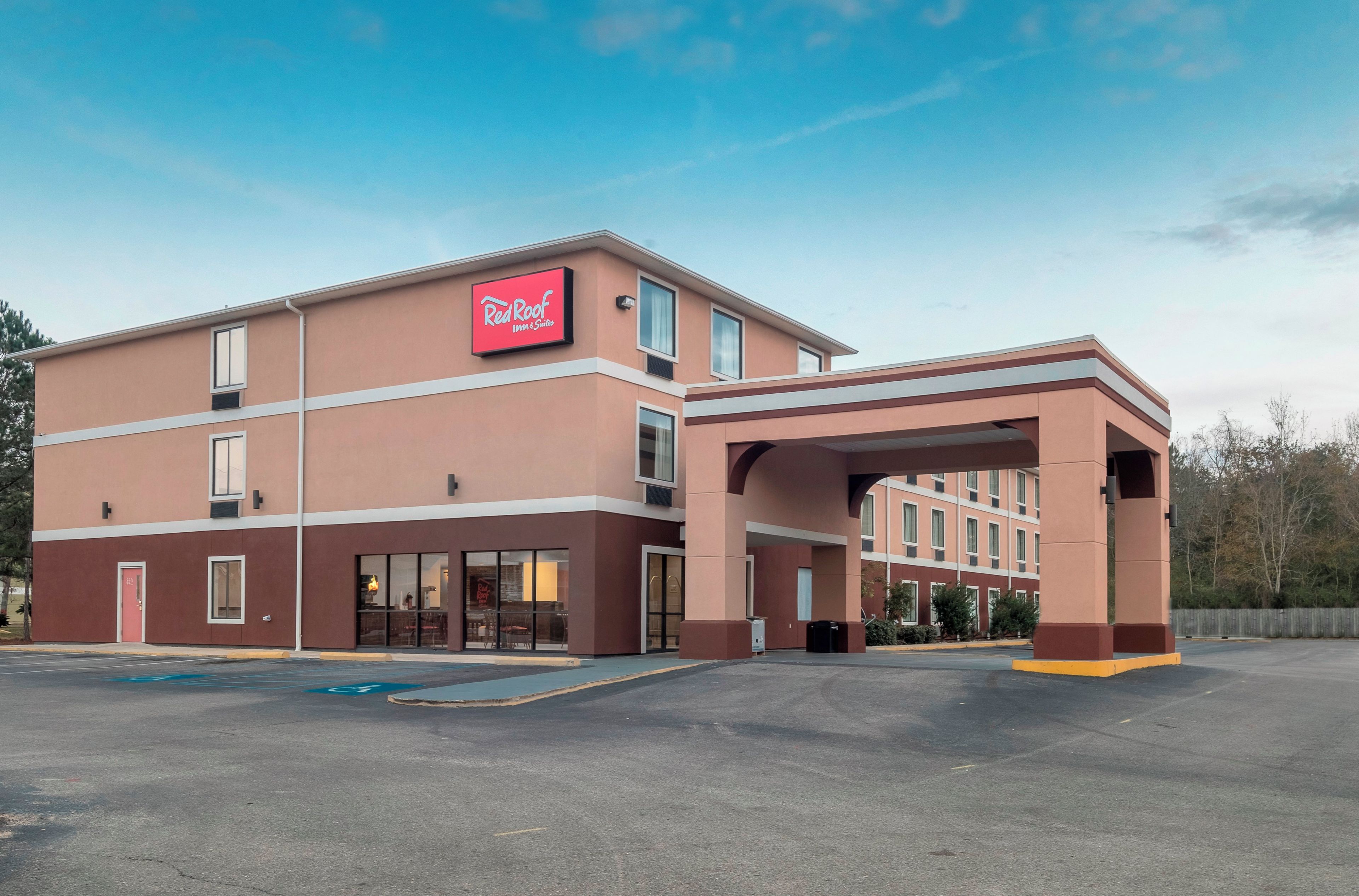 Un Red Roof Inn & Suites con entrada cubierta y estacionamiento.