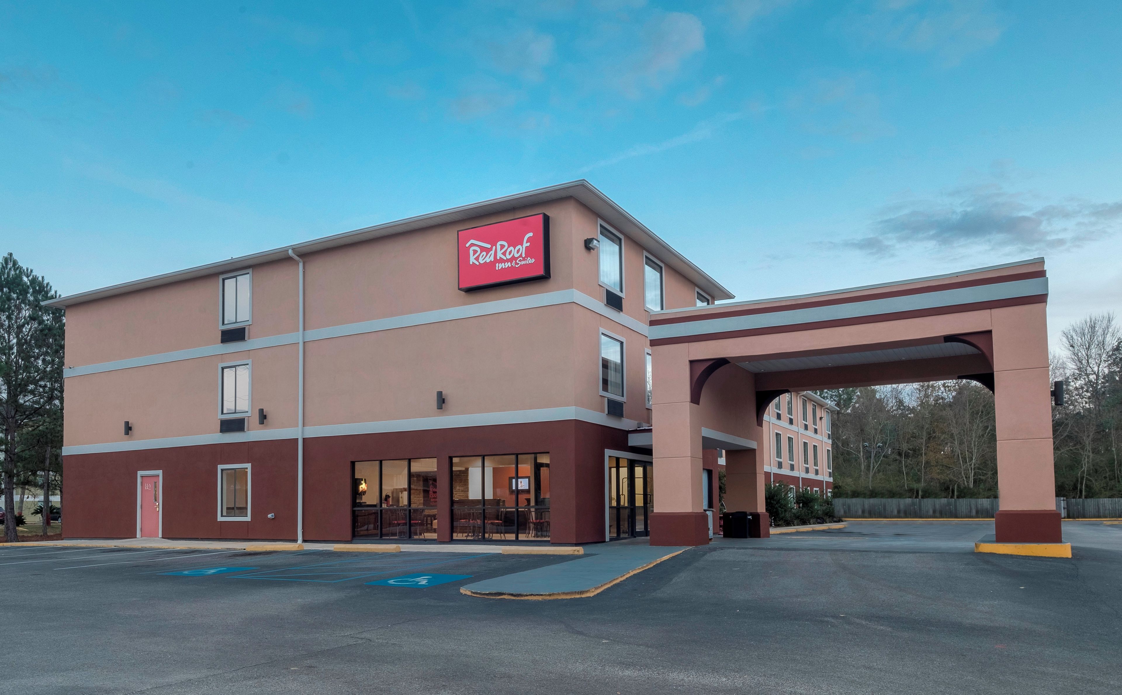 Ein Red Roof Inn & Suites mit überdachtem Parkplatz und blauem Himmel.