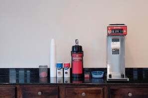 Angolo caffè con macchina da caffè, panna, zucchero e bicchieri usa e getta.