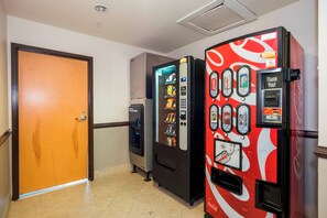 Un pasillo con máquinas expendedoras, una puerta y suelo de baldosas.