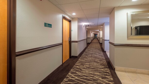 Um corredor de hotel com placas indicando as direções para os quartos e o saguão.