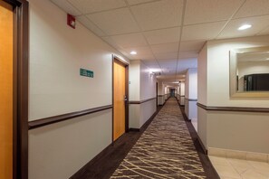 Un pasillo de hotel con carteles indicativos hacia las habitaciones y la recepción.