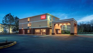 Un hotel Red Roof Inn & Suites de dos pisos, con un acceso cubierto y estacionamiento.