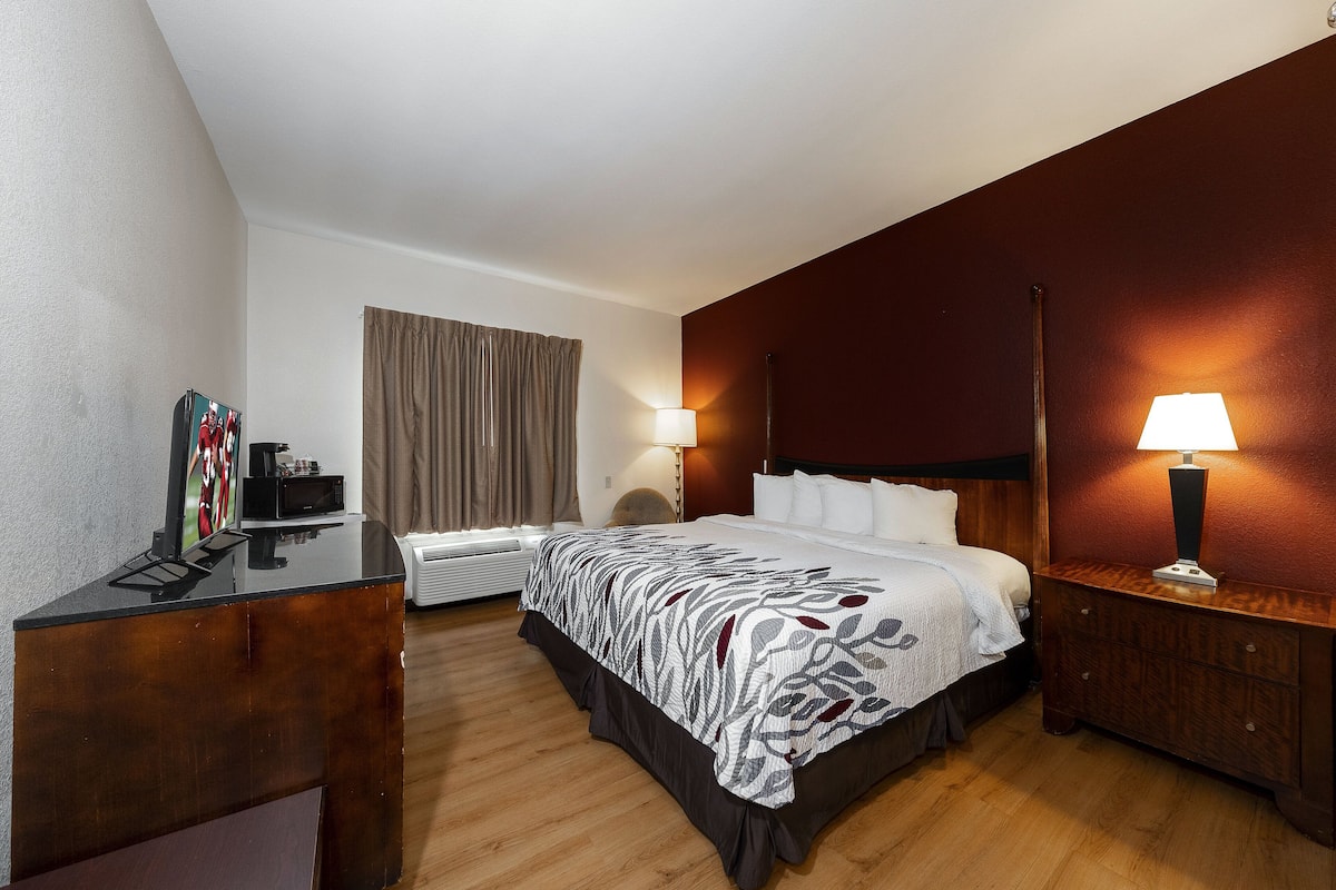 Ein Hotelzimmer mit Bett, Nachttischen, Schreibtisch und Fernseher.