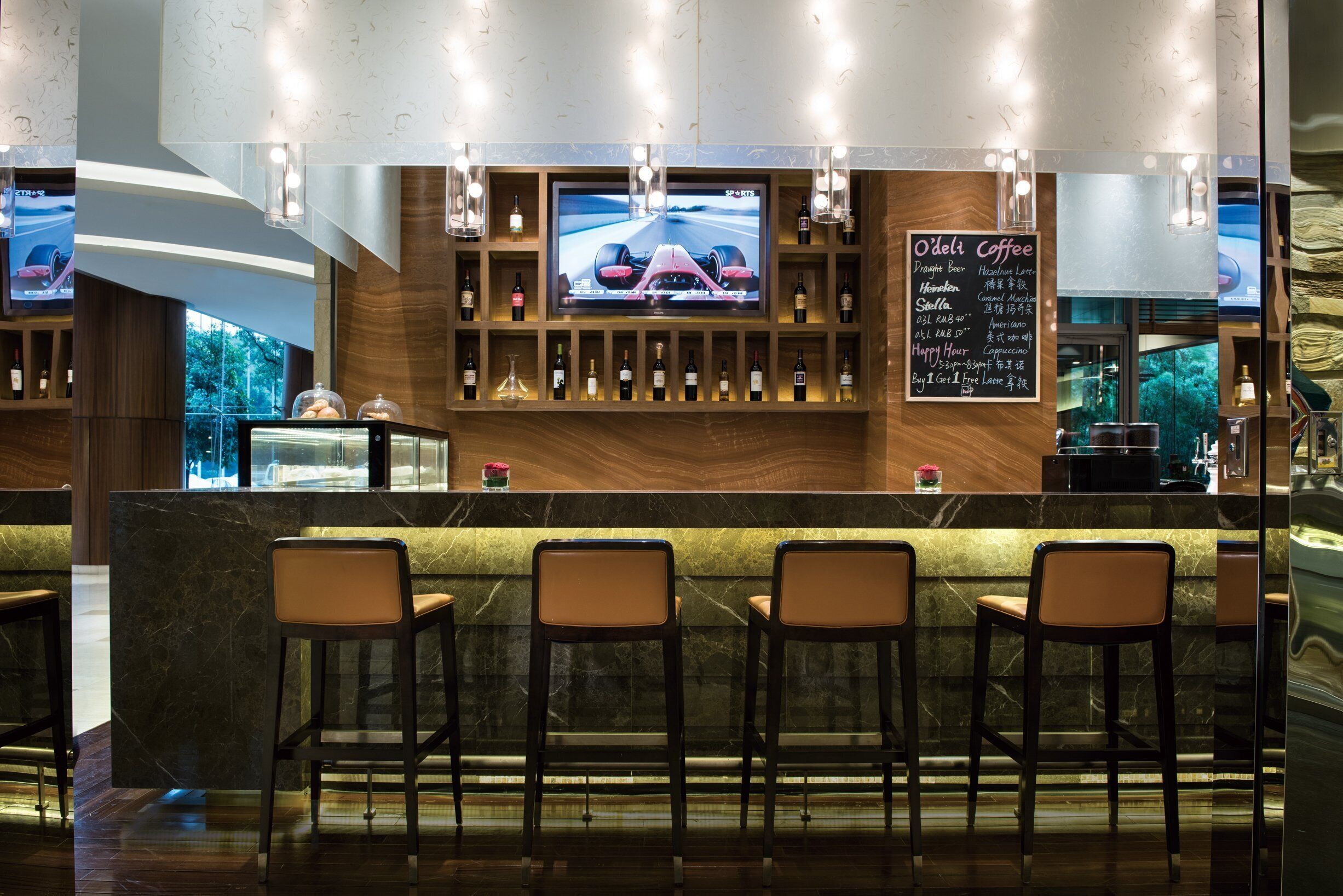 A bar area with a TV screen displaying a racing car, shelves with bottles, and a menu board.