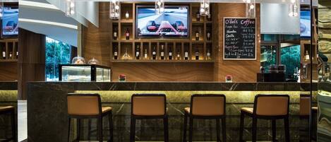 A bar area with a TV screen displaying a racing car, shelves with bottles, and a menu board.