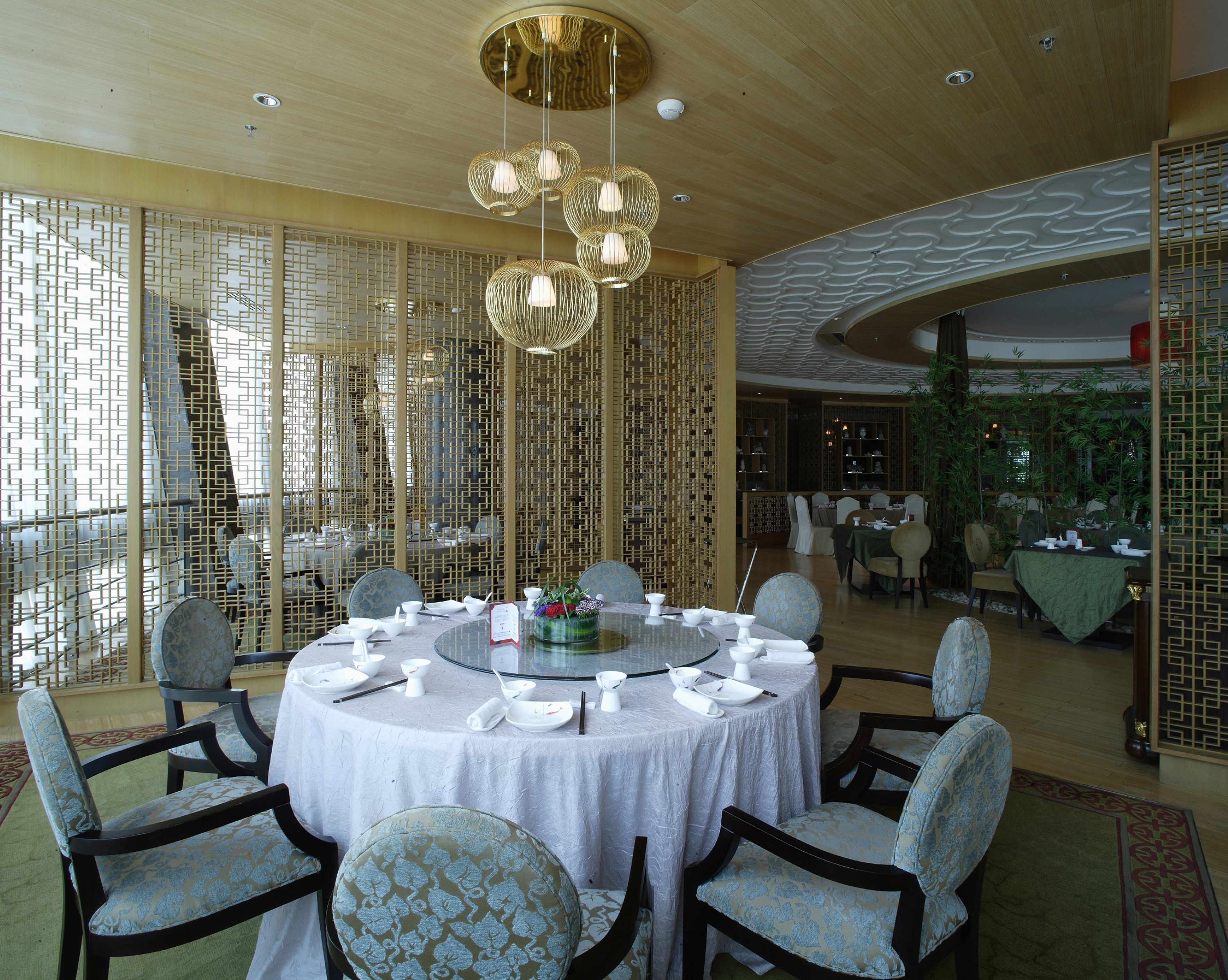 A dining area with round tables, chairs, and a decorative ceiling.
