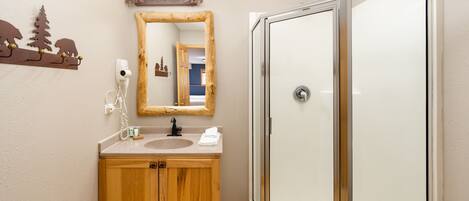 A bathroom with a wooden vanity, a mirror, a shower enclosure, and a wall-mounted towel rack.