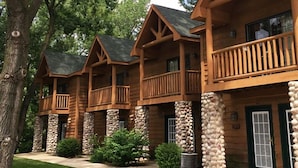 A row of log cabin-style buildings with balconies and stone pillars.
