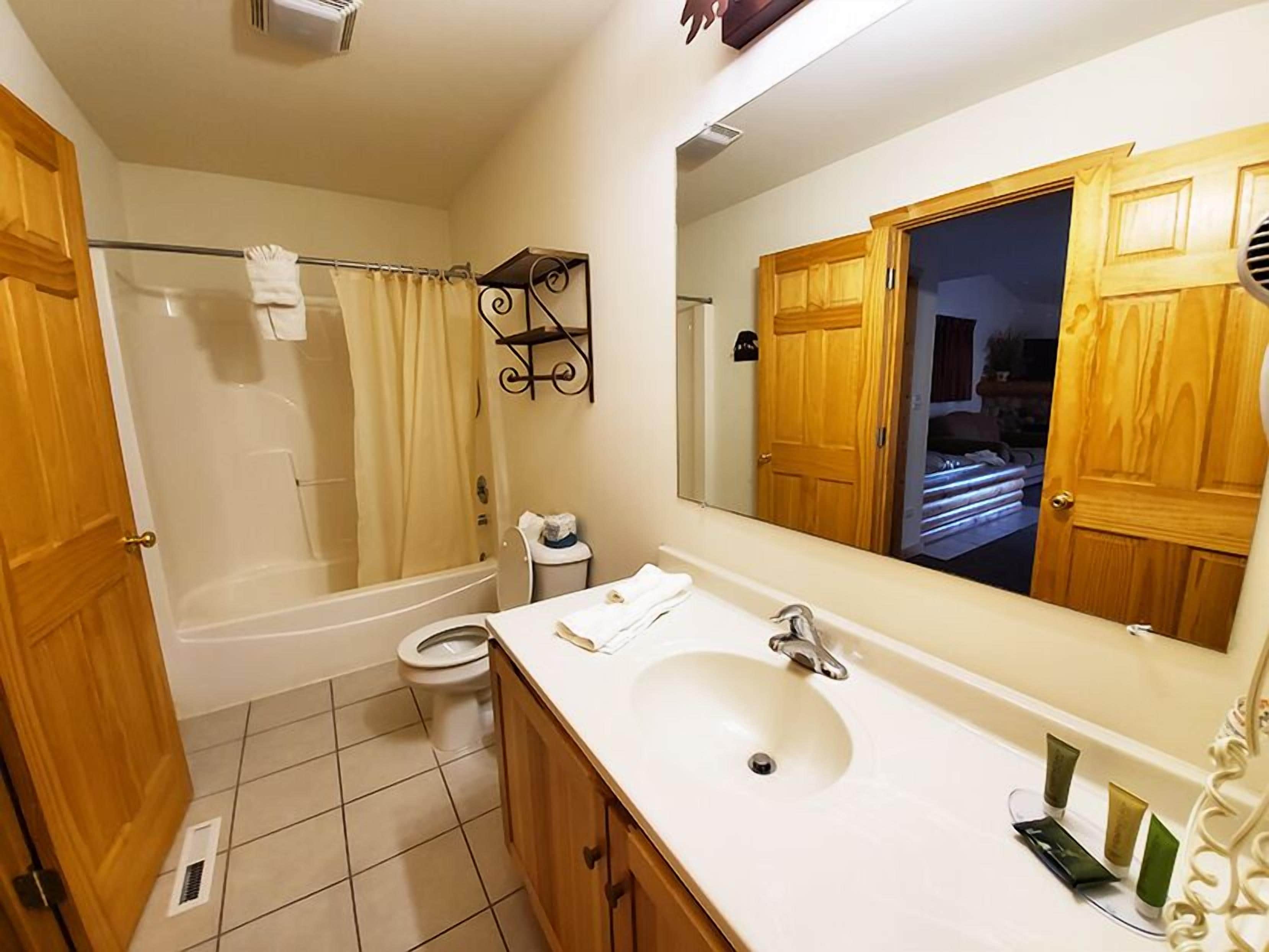 A bathroom with a bathtub, toilet, sink, and a large mirror.