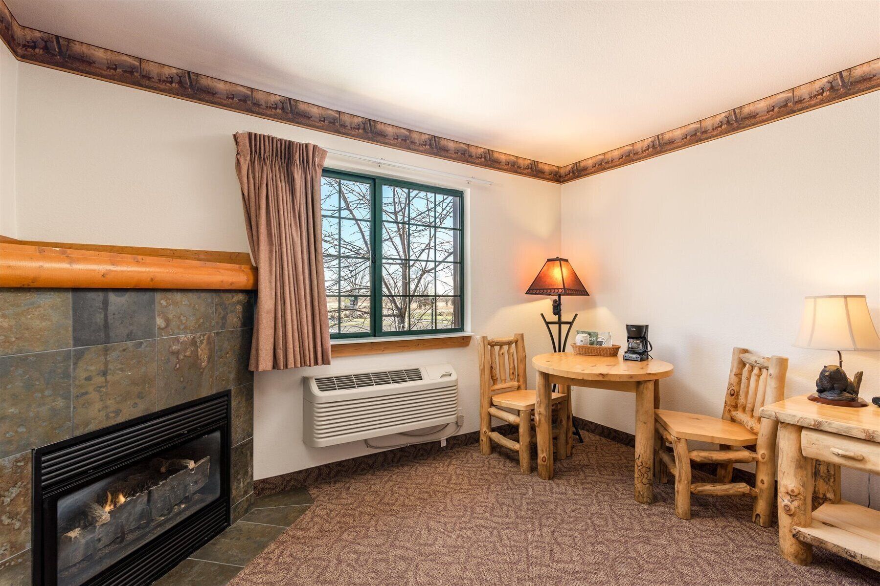 Una habitación acogedora con chimenea, una ventana con cortinas, una mesa con sillas y una lámpara.