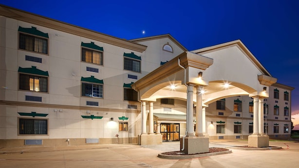 A hotel entrance with a covered waiting area, multiple windows, and a night sky with a visible moon. - Best Western Henrietta Inn & Suites (Henrietta)