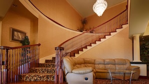 A grand staircase with a wooden railing, a leather sofa, and a chandelier. - Best Western Henrietta Inn & Suites (Henrietta)