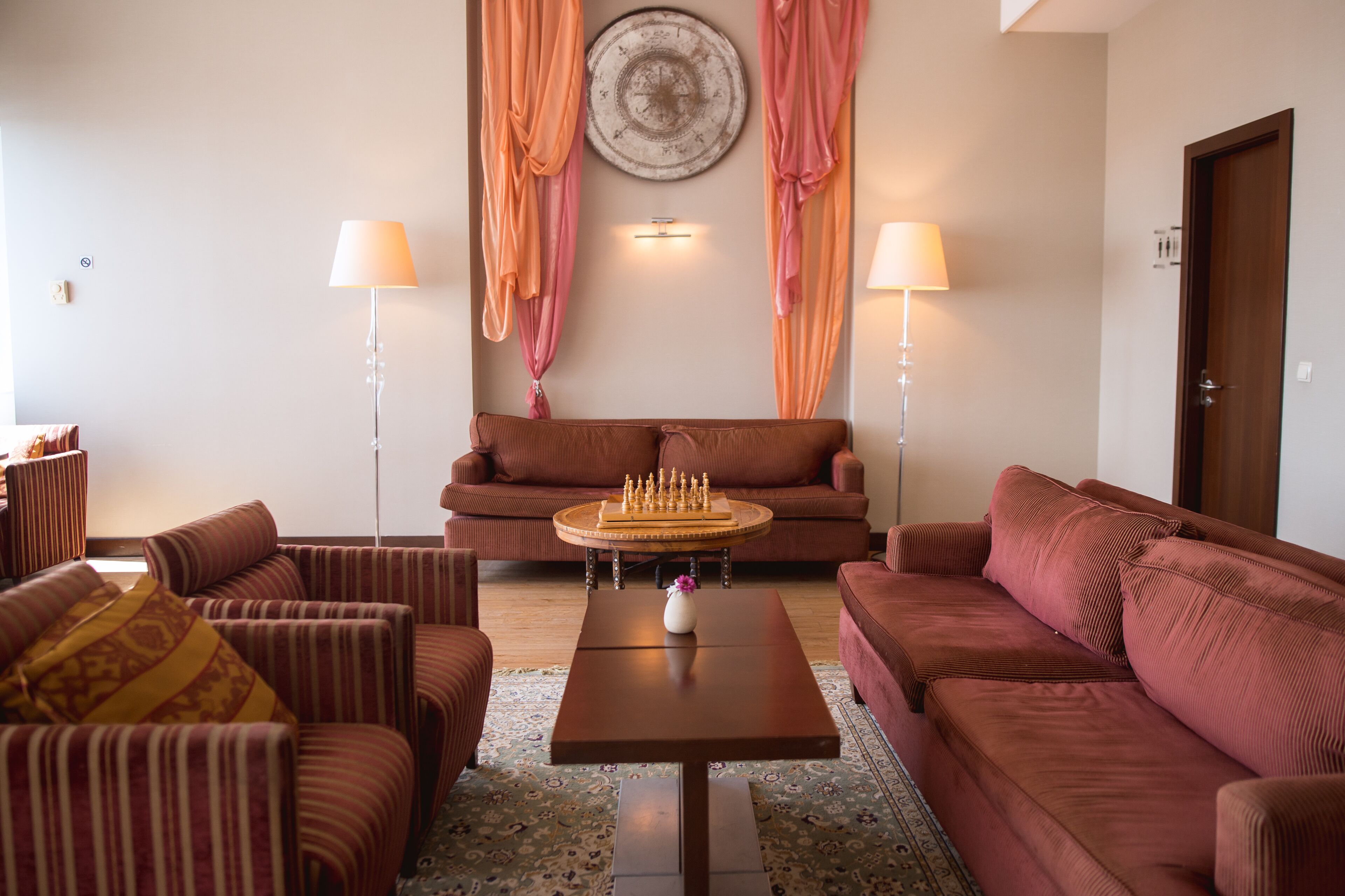 A living room with striped sofas, a coffee table with a chess set, and two lamps.