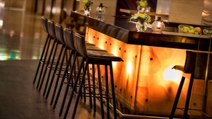 A bar area with a long counter, multiple stools, and decorative elements like flowers and candles.