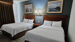 A hotel room with two beds, wooden headboards, a nightstand with lamps, and two framed pictures on the wall. - Sierra Huasteca Inn (Ciudad Valles)
