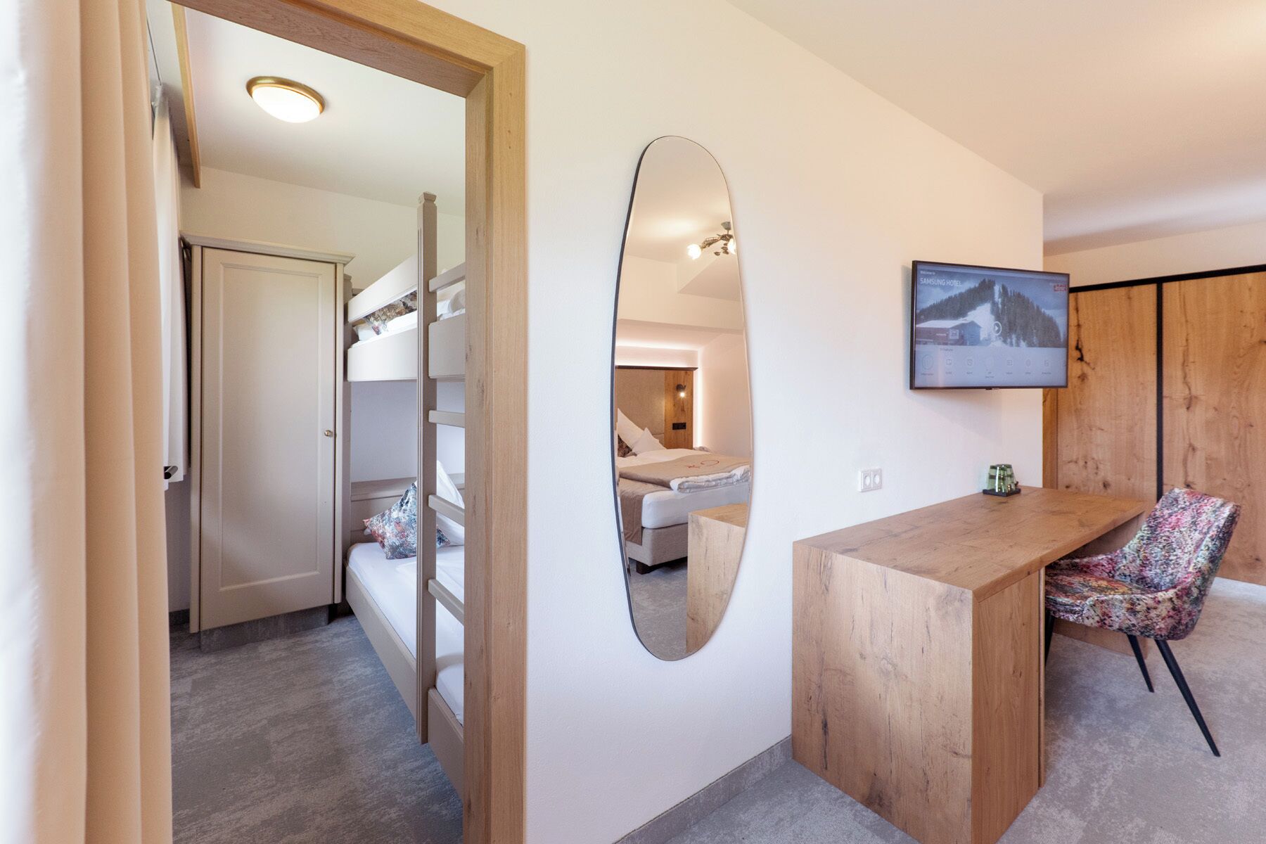 Een hotelkamer met een bed, een bureau, een stoel, een spiegel en een televisie.