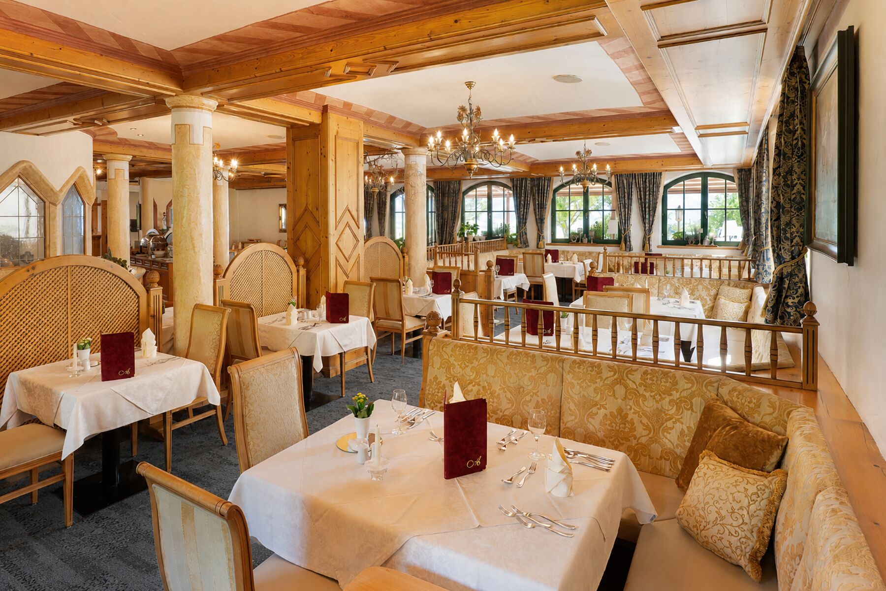 Un restaurante con vigas de madera, candelabros y mesas dispuestas para comer.