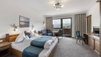 Una camera d'albergo con un letto grande, una scrivania, una sedia, una TV e una finestra vista montagna.